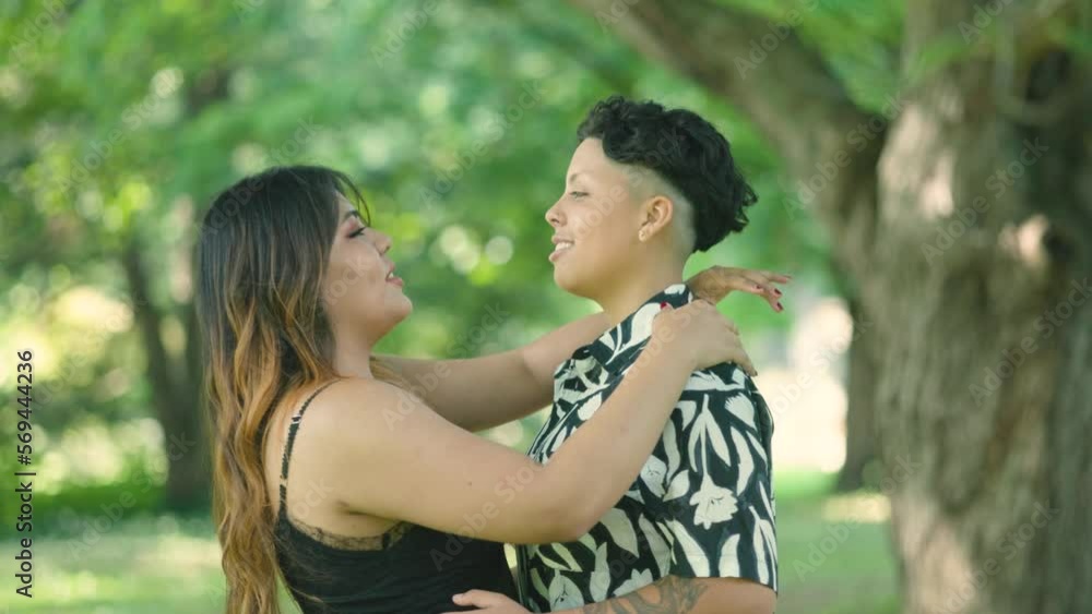 Two Latin lesbian women embrace in park, showcasing love and diversity. Ideal for LGBTQ+ advocacy projects. Slow-motion captures unity, inclusiveness, and diversity in a symbol of love and acceptance. Two Latin lesbian women embrace in park, showcasing love and diversity. Ideal for LGBTQ+ advocacy projects. Slow-motion captures unity, inclusiveness, and diversity in a symbol of love and acceptance.