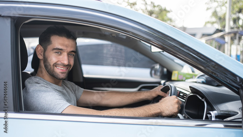 Happy man driving a car and smiling. Cute young Hispanic male success happy brunette. Portrait of happy driver steering car Holiday.