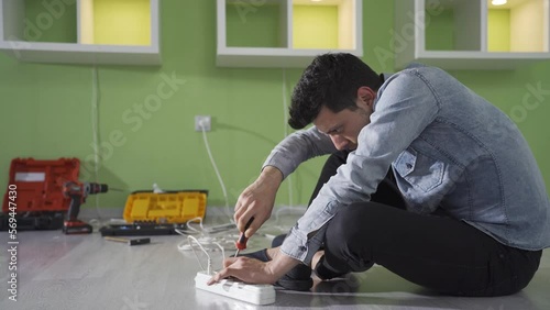 Clumsy and insecure young man gets electrocuted while repairing a socket at home. The incompetent man with no job security was electrocuted while repairing the sockets in his house.
 photo