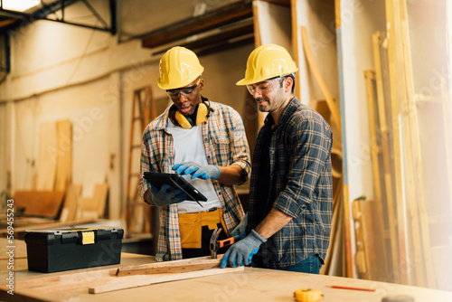 Two Carpenter working on wood craft at workshop to produce construction material or wooden furniture. The young carpenter use professional tools for crafting. DIY maker and carpentry work concept.