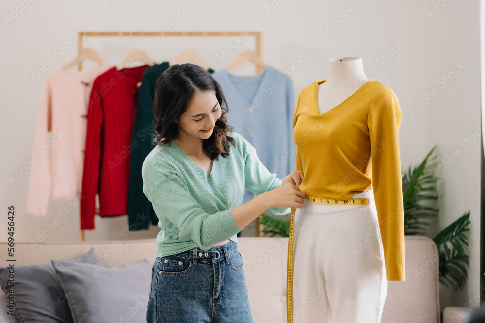 Fashion designer l young asian woman working using laptop, tablet and smiling while standing in workshop Responding on business e-mail.. Fashion designer l young asian woman working using laptop, tablet and smiling while standing in workshop Responding on business e-mail..