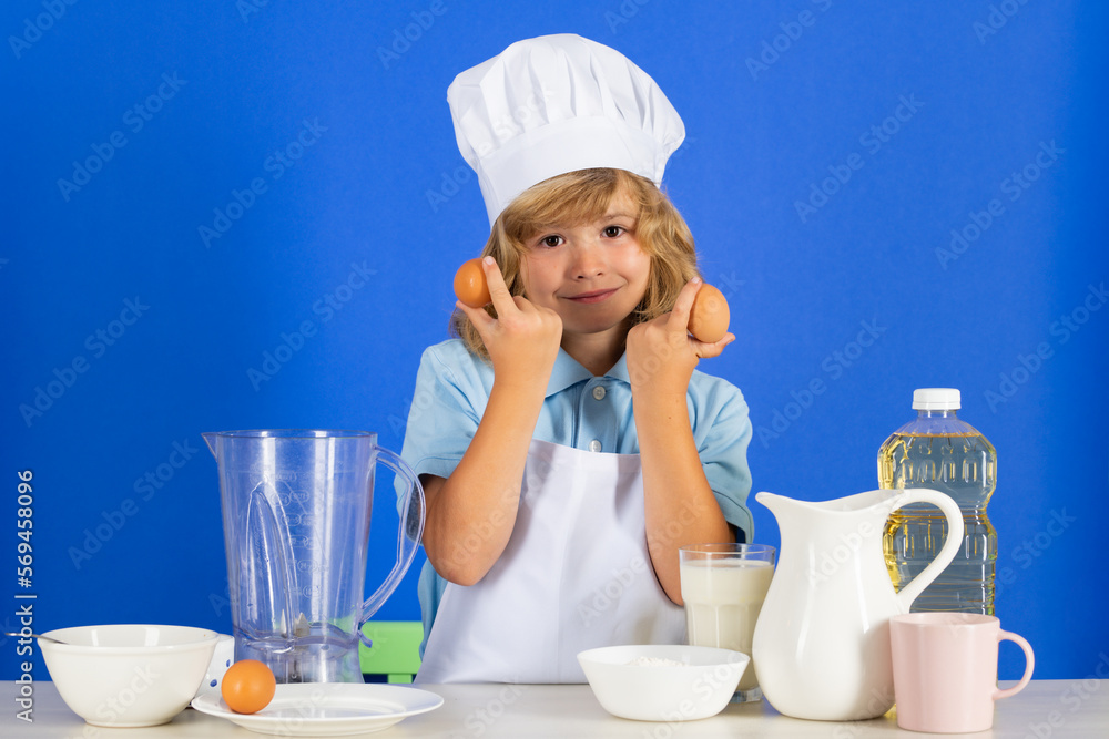 Child chef dressed cook baker apron and chef hat hold eggs isolated on studio background. Healthy nutrition kids food. Child chef dressed cook baker apron and chef hat hold eggs isolated on studio background. Healthy nutrition kids food.