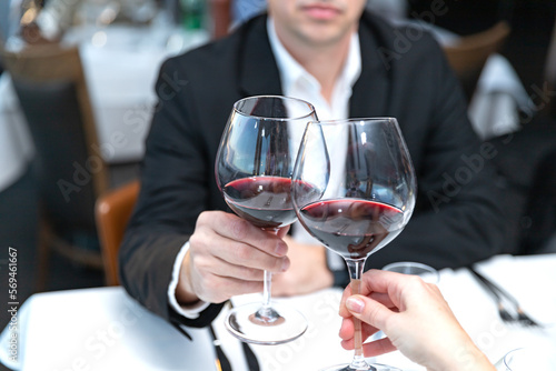 Couple of lovers with glasses of red wine sitting in restaurant