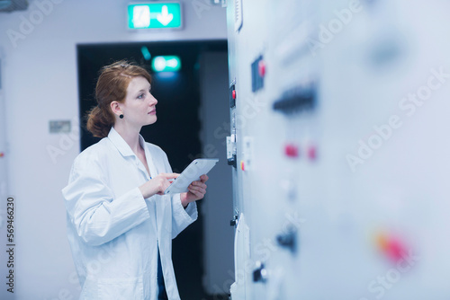 Young female engineer updating control panel using digital tablet in an industrial plant, Freiburg im Breisgau, Baden-Württemberg, Germany