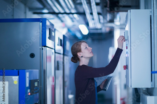 Young female engineer controlling a switchgear in control room, Freiburg im Breisgau, Baden-Württemberg, Germany photo