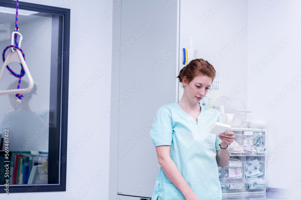 Nurse holding medicine while standing in store room at hospital Nurse holding medicine while standing in store room at hospital