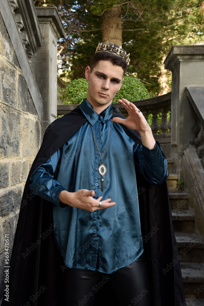 Close up portrait of handsome brunette man wearing fantasy medieval prince costume with golden crown and romantic silk shirt. historical castle location background. Close up portrait of handsome brunette man wearing fantasy medieval prince costume with golden crown and romantic silk shirt. historical castle location background.