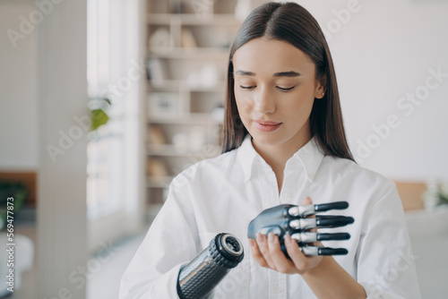 Disabled young woman is assembling bionic arm. Software and buttons  fingers and palm.