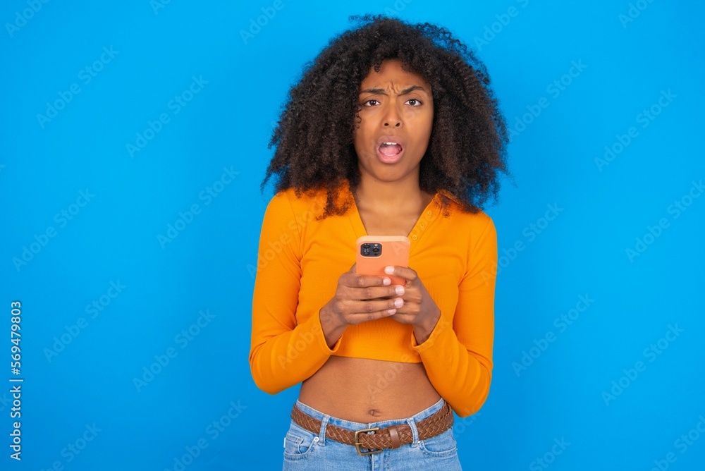 Photo of interested young beautiful brunette woman wearing colourful dress over white wall hold telephone look side empty space screen Photo of interested young beautiful brunette woman wearing colourful dress over white wall hold telephone look side empty space screen