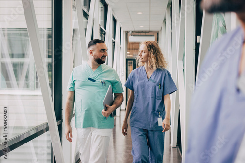 Multiracial male and female hospital staff walking in corridor photo