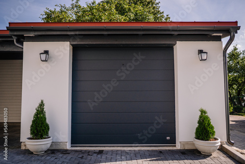 Modern gray garage, next to the Scandinavian-style house. Private garage with automatic door in a European 