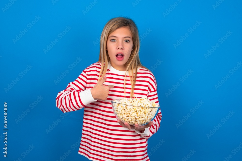 Embarrassed beautiful caucasian teen girl wearing striped T-shirt indicates at herself with puzzled expression, being shocked to be chosen to participate in competition, hesitates about something Embarrassed beautiful caucasian teen girl wearing striped T-shirt indicates at herself with puzzled expression, being shocked to be chosen to participate in competition, hesitates about something