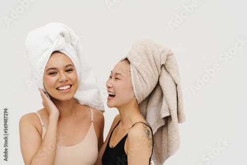 Two beautiful women laughing while posing isolated over white wall