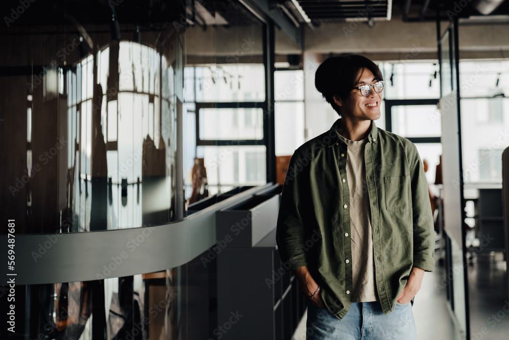 Positive asian business man walking through modern office space