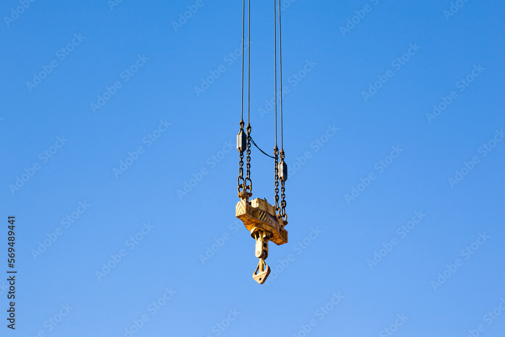 Crane hook stabilizer hanging on cables against the blue sky. Crane hook stabilizer hanging on cables against the blue sky.