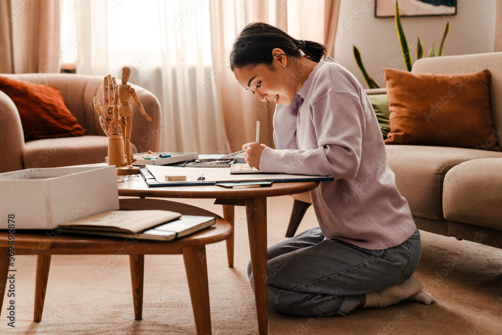 Asian woman drawing on digital tablet with stylus while sitting at table Asian woman drawing on digital tablet with stylus while sitting at table