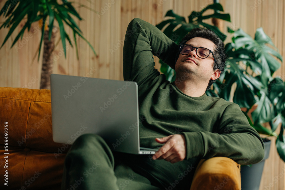 thirty-year-old man with laptop sitting at home on the couch
