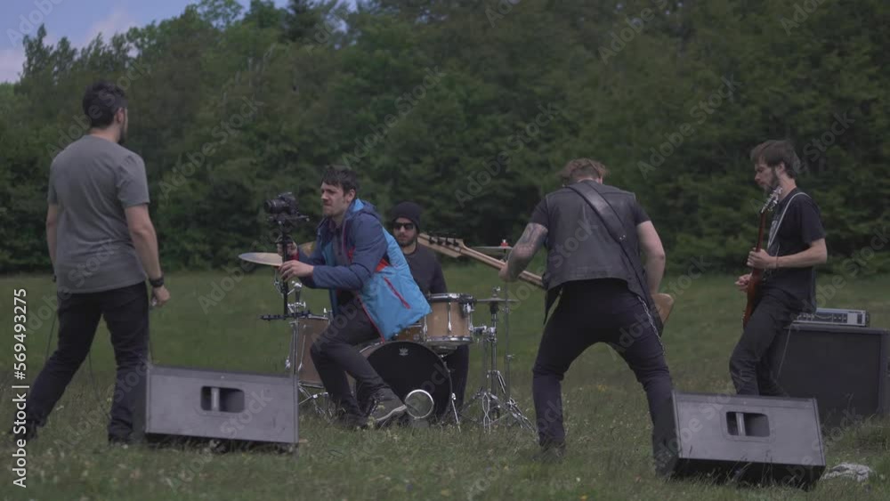 A man is filming and making the video clip of a rock band outside, sun A man is filming and making the video clip of a rock band outside, sun