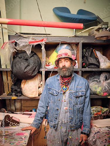 Portrait of eclectically dressed artist in his art making space. photo