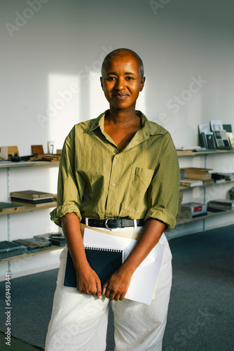 Portrait of confident smiling businesswoman holding document while standing in office