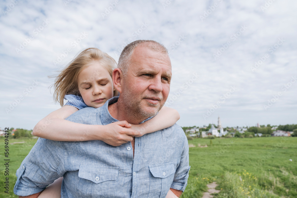 Fototapeta premium Daughter embracing father carrying her piggyback.
