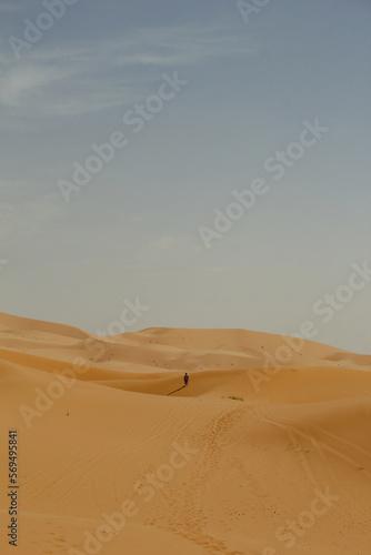 Abstract photograph of an unrecognizable person in the middle of a sand dune shot at sunset in Merzouga, Morocco