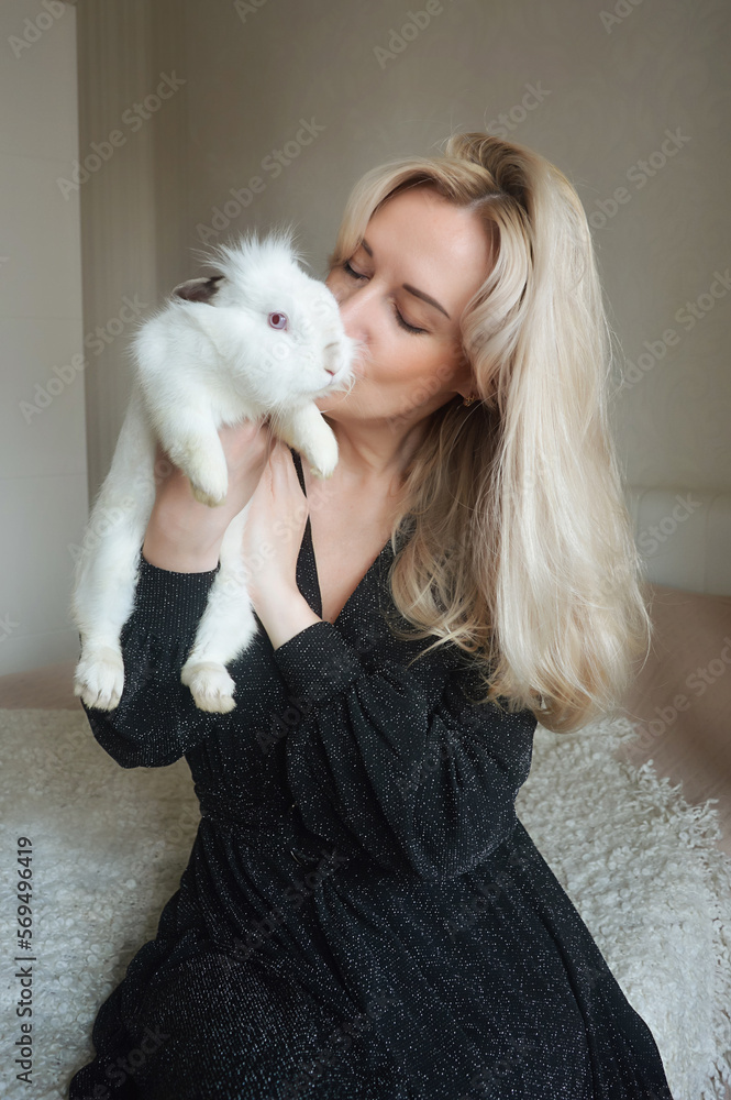 beautiful young blonde woman holding a white rabbit. pets. background for decoration for the holidays. Happy Easter beautiful young blonde woman holding a white rabbit. pets. background for decoration for the holidays. Happy Easter
