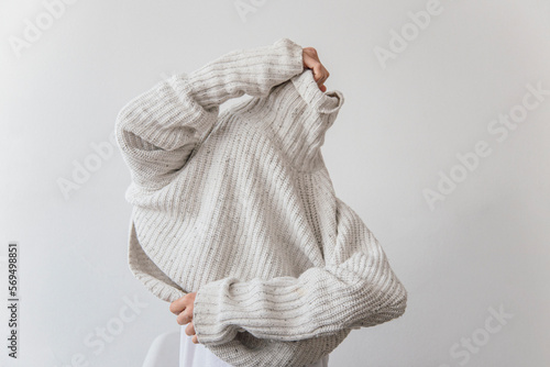 Quadro em tela Unrecognizable female getting dressed in a wool winter sweater shot in a studio