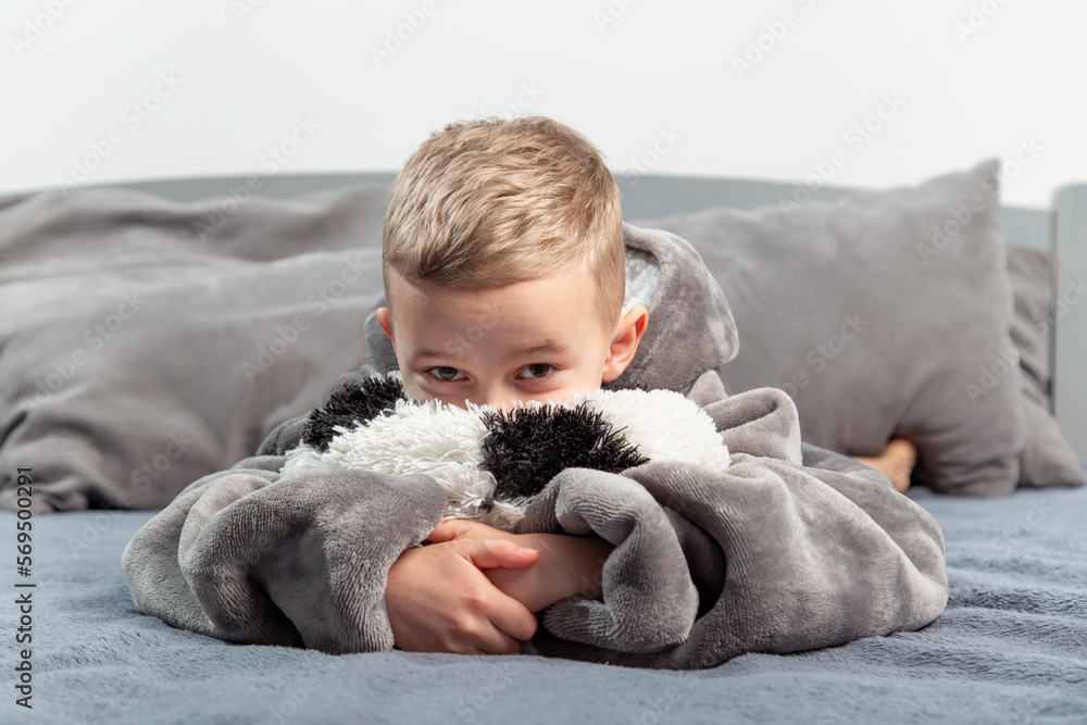 A six-year-old boy plays with a stuffed toy in the form of a soccer ball on the bed.A six-year-old boy plays with a stuffed toy in the form of a soccer ball on the bed.hugs the ball A six-year-old boy plays with a stuffed toy in the form of a soccer ball on the bed.A six-year-old boy plays with a stuffed toy in the form of a soccer ball on the bed.hugs the ball