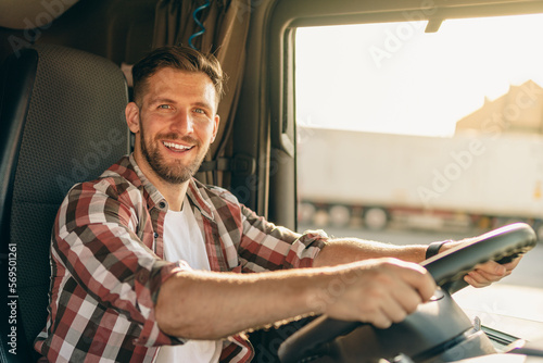 Professional middle aged truck driver in casual clothes driving truck vehicle going for a long transportation route. photo