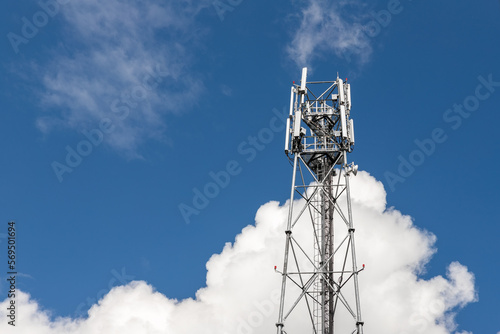 Bottom perspective pov of modern metal steel mobile 5g network wireless telecom tower against clear blue sky background on bright day. Microwave signal broadband equipment base line station mast