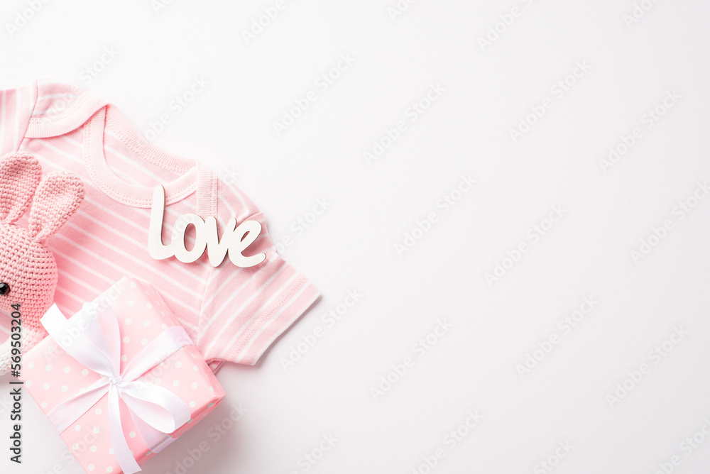 Baby girl concept. Top view photo of pink shirt giftbox with bow inscription love and knitted bunny rattle toy on isolated white background with empty space