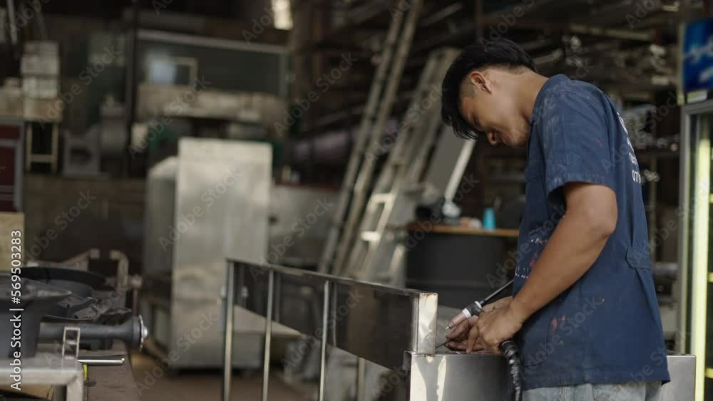 Real factory laborer using a welding gun and smiling to the camera Real factory laborer using a welding gun and smiling to the camera