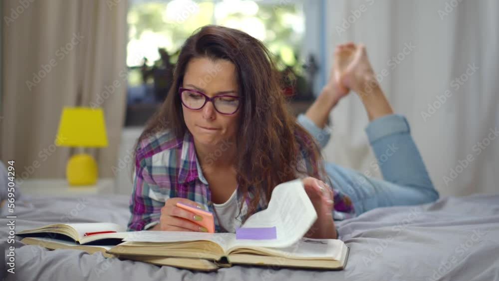 Young woman lying on bed at home and reading book. Realtime Young woman lying on bed at home and reading book. Realtime
