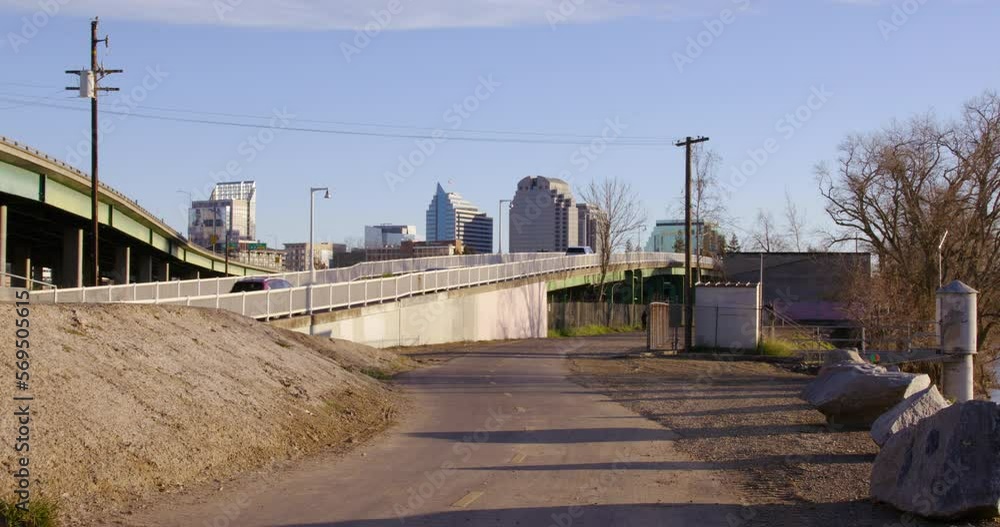 Cars ascend the ramp to send them southeast towards J Street in Sacramento, California. A pedestrian trail sits to the right of this ramp and the highway is on the left. Cars ascend the ramp to send them southeast towards J Street in Sacramento, California. A pedestrian trail sits to the right of this ramp and the highway is on the left.