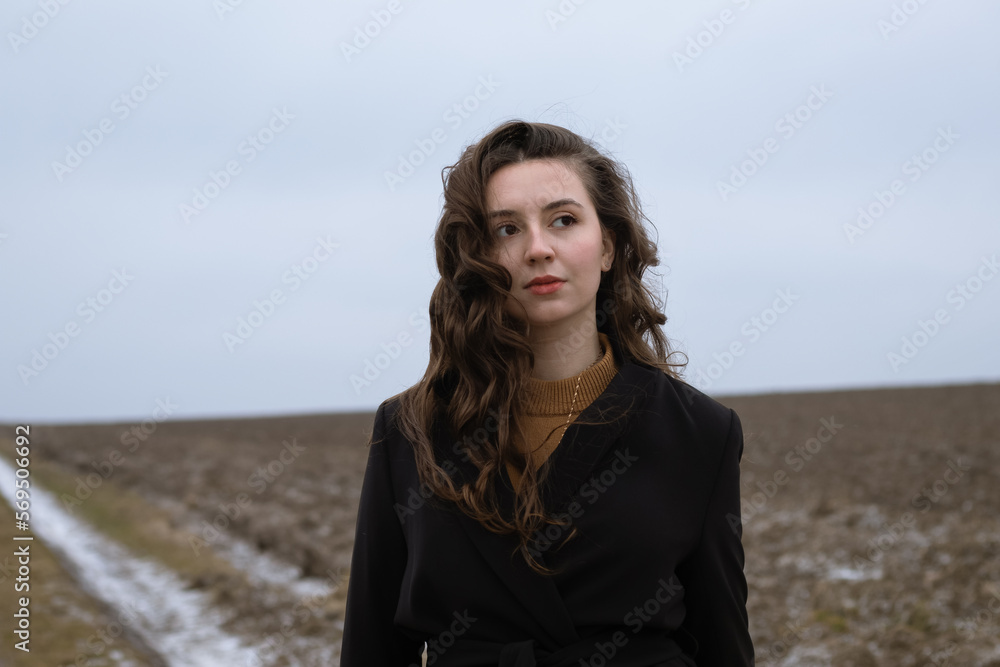 A beautiful girl is standing in a field.Natural beauty.Curly brunette.Emotions of calmness and reflection.Woman dreams.Lady in black.Portrait of a young woman.Retro and vintage.Deep beautiful look. A beautiful girl is standing in a field.Natural beauty.Curly brunette.Emotions of calmness and reflection.Woman dreams.Lady in black.Portrait of a young woman.Retro and vintage.Deep beautiful look.