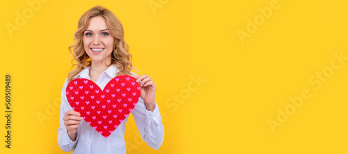 glad woman with red love heart on yellow background. Woman isolated face portrait, banner with mock up copy space.