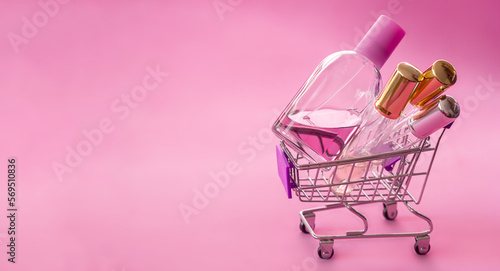 Mini supermarket trolley with glass test tubes, bottles with samplers of perfumes, cosmetic products, fake cosmetics and perfumes, selective focus	