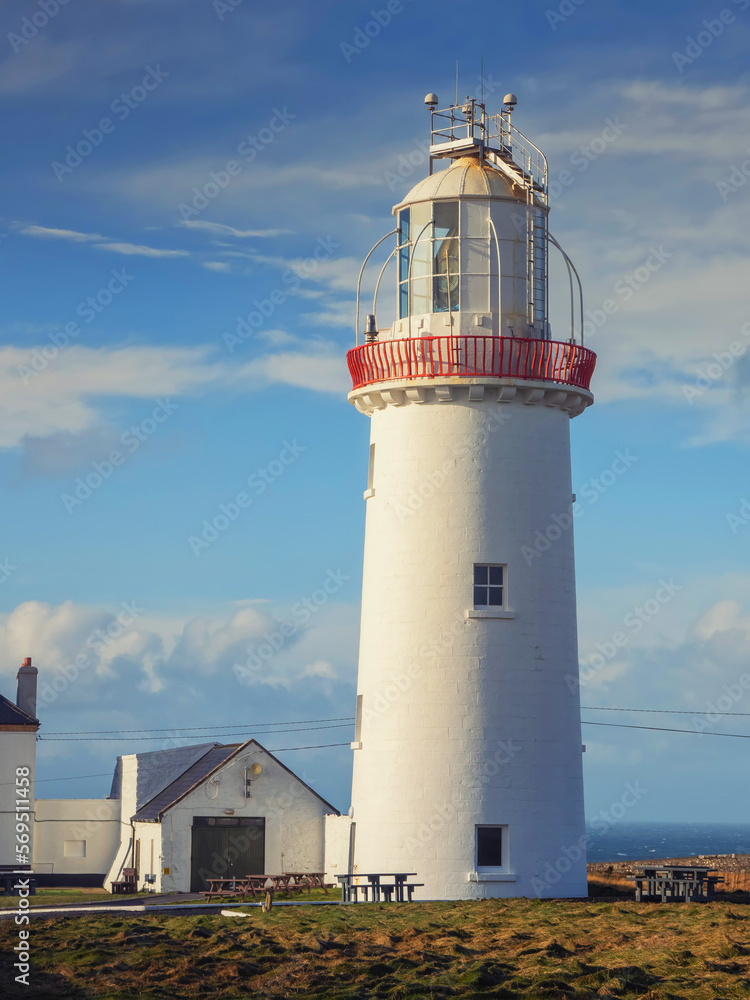 Loop head light house in classic white color against blue cloudy sky. County Clare, Ireland, Popular travel area for history trip and sightseeing.