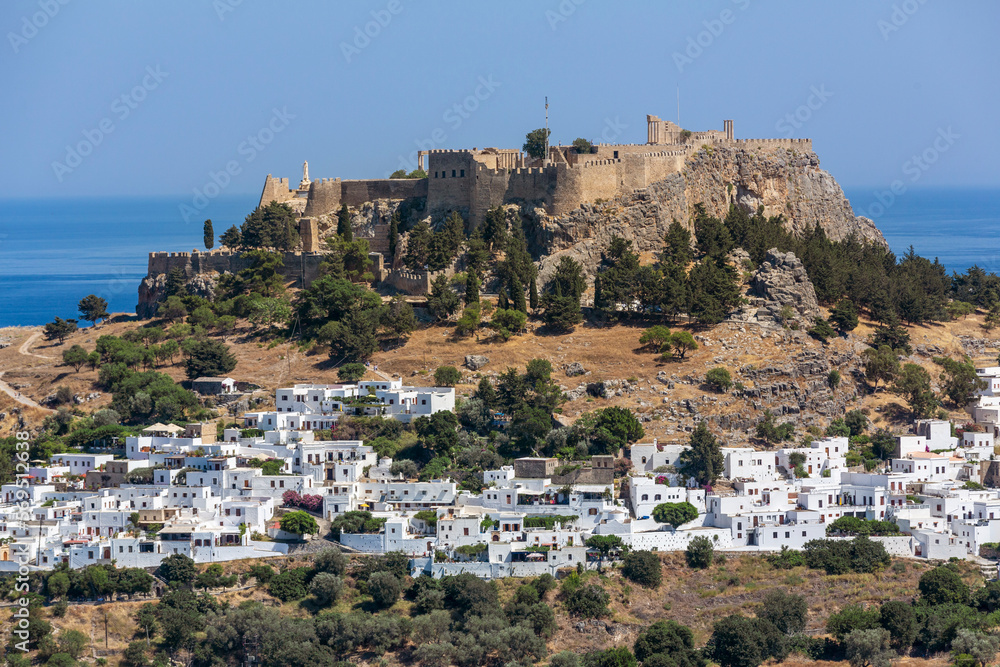 View on View of Lindos village   and ruins with  Acropolis on a hill out of the water in Lindos, Rhodes, Greece.