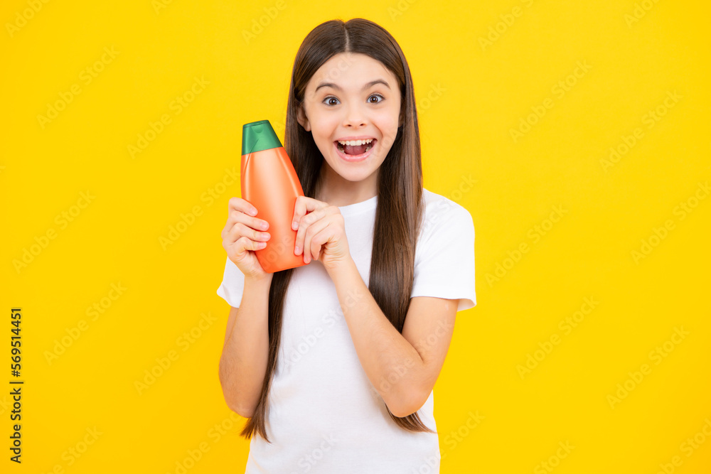 Teenager child girl showing bottle shampoo conditioners or shower gel isolated on yellow background. Hair cosmetic product. Mock up bottle. Excited teenager, glad amazed and overjoyed emotions. Teenager child girl showing bottle shampoo conditioners or shower gel isolated on yellow background. Hair cosmetic product. Mock up bottle. Excited teenager, glad amazed and overjoyed emotions.