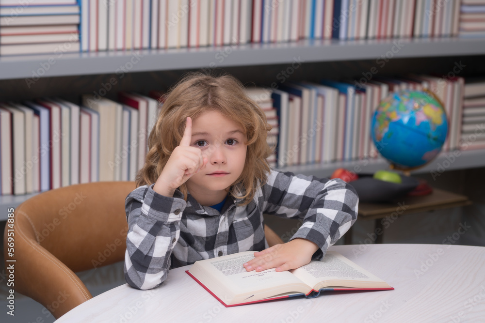 Education, knowledge and bookstore concept. Child reading a red book in the library. Little student on school library. Education, knowledge and bookstore concept. Child reading a red book in the library. Little student on school library.
