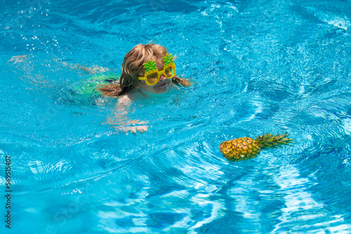 Happy kid in swimming pool on summer day. Child play in tropical resort. Summer vacation.