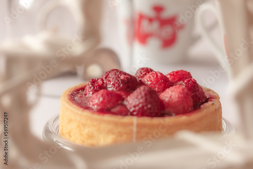 A tasty sweet tart with fresh berries in a white frame. Appetizing close up of a fruit tart consisting of raspberries