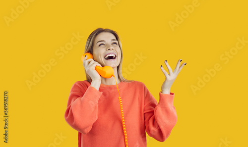 Bilde på lerret Happy young excited woman talking on landline phone isolated on yellow background