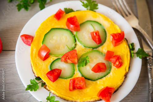 Fried omelet with zucchini, tomatoes, herbs in a plate