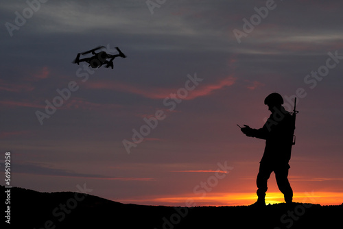 Silhouettes of soldiers are using drone and laptop computer for scouting during military operation against the backdrop of a sunset. Greeting card for Veterans Day, Memorial Day, Independence Day.