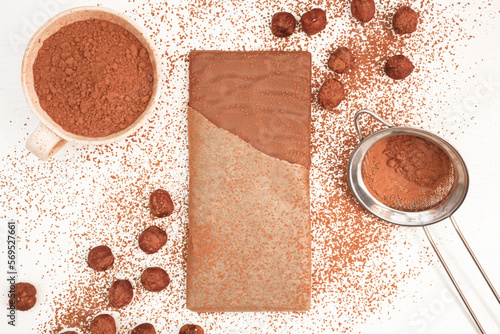 Chocolate bar with hazelnuts around it sprinkled with cocoa