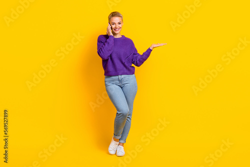 Full size portrait of attractive girl communicate telephone arm palm hold empty space isolated on yellow color background