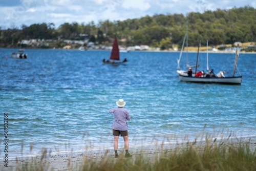 man watching wooden boat on the water, at the wooden boat festival in hobart tasmania australia